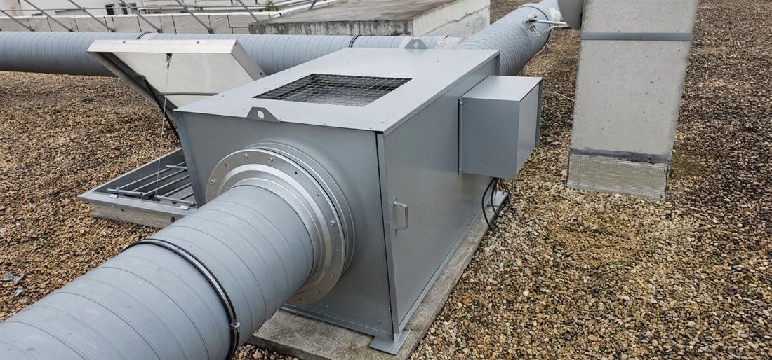 Caisson d'extraction neuf posé sur son socle en toiture, raccordé à un réseau de gaines et à son coffret de commande